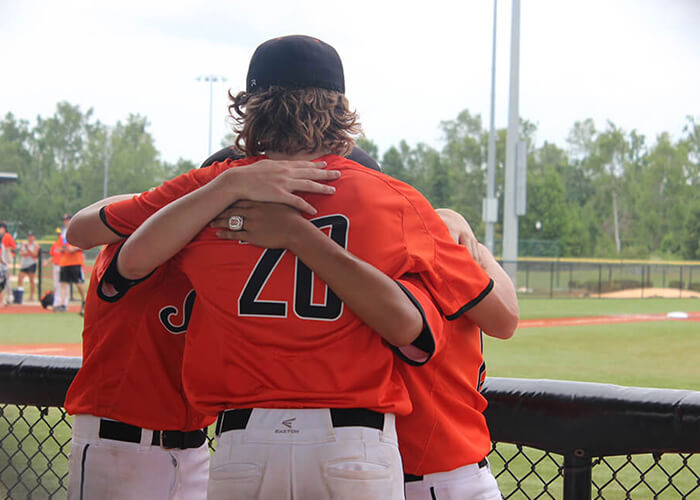 Young Kevin White huddling with his teammates wearing his orange St. Charles Saints jersey.